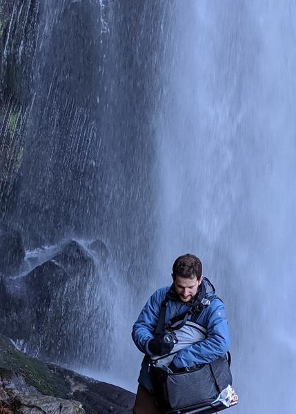"Moi, en face d'une cascade, cherchant mon équipement dans mon sac à dos"